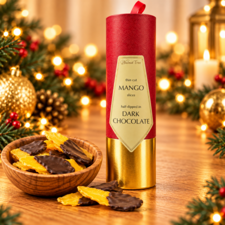 Walnut Tree luxury gift scroll containing thin-cut mango slices half-dipped in dark chocolate, presented in red and gold packaging with a wooden bowl of chocolate-dipped mango and warm Christmas lights.