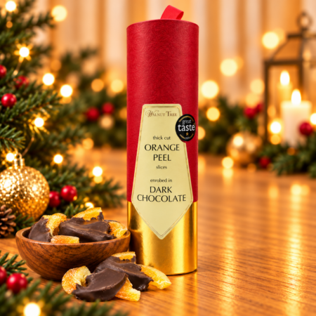 Walnut Tree luxury Christmas gift scroll containing dried apricot slices half-dipped in dark chocolate, presented in red and gold packaging with a wooden bowl of chocolate apricots, festive greenery and warm golden Christmas lights.