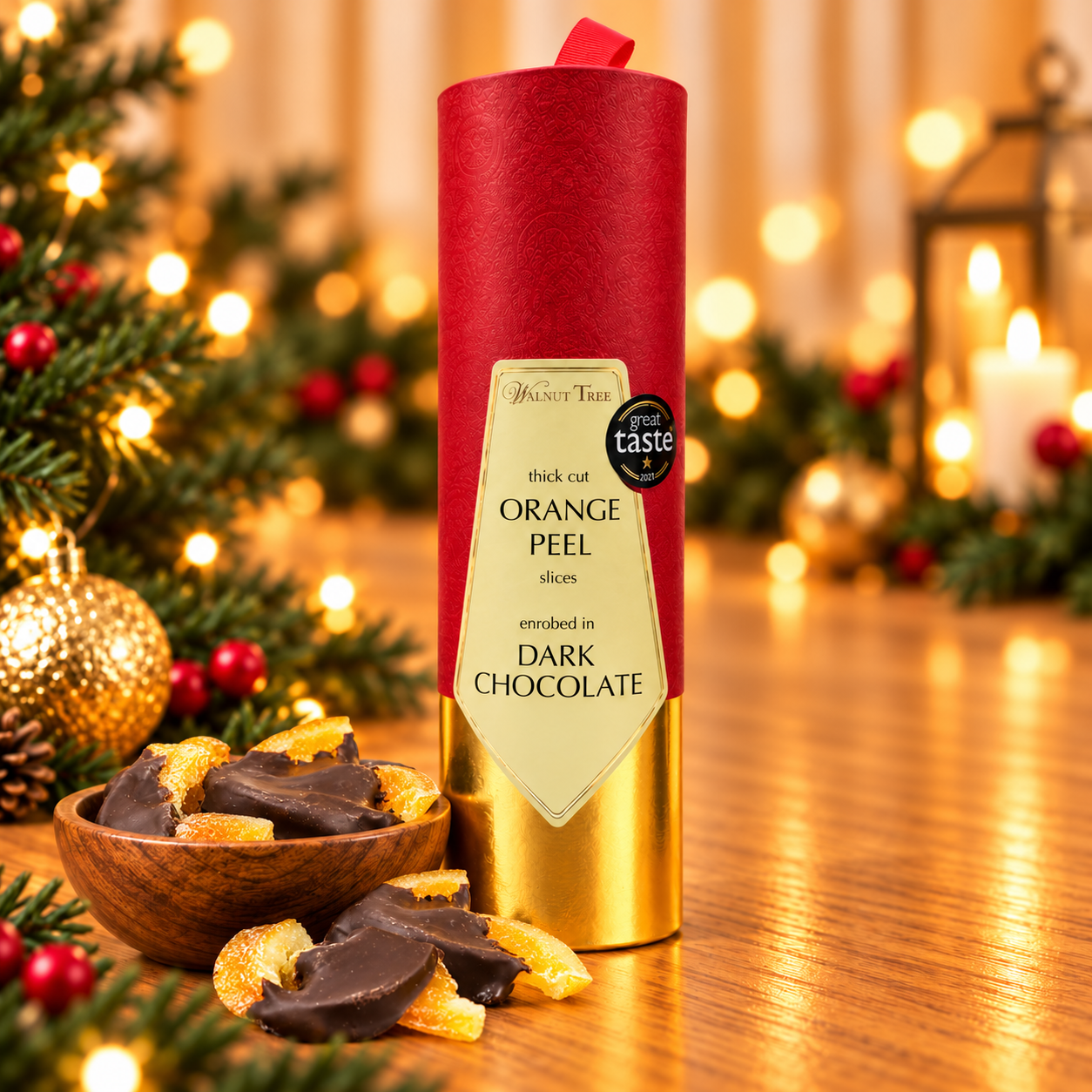 Walnut Tree luxury Christmas gift scroll containing dried apricot slices half-dipped in dark chocolate, presented in red and gold packaging with a wooden bowl of chocolate apricots, festive greenery and warm golden Christmas lights.