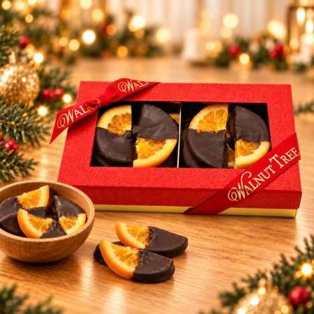 Walnut Tree luxury medium gift box of dark chocolate-dipped orange slices, presented in a red patterned box with metallic gold Walnut Tree ribbon, wooden bowl and elegant Christmas decorations.