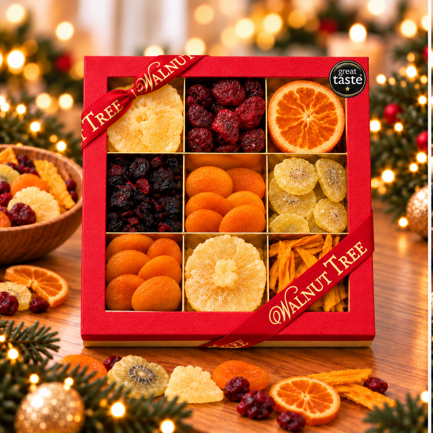 Walnut Tree luxury nine-compartment dried fruit gift box featuring assorted dried and glacé fruits, presented in red packaging with gold ribbon and Great Taste award badge against a warm Christmas background.