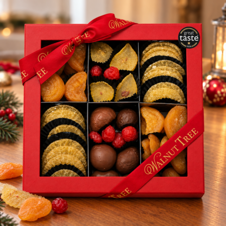 Walnut Tree luxury nine-compartment glacé fruit gift box featuring assorted candied citrus slices and colourful glacé fruits, presented in red packaging with gold ribbon and Great Taste award badge against a festive Christmas background.