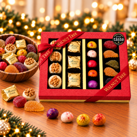 Walnut Tree SCCC luxury four-compartment confectionery gift box featuring walnut-topped marzipan, marrons glacés, colourful sweets and glacé fruits, presented in red packaging with gold ribbon and a Great Taste award badge against a festive Christmas background.