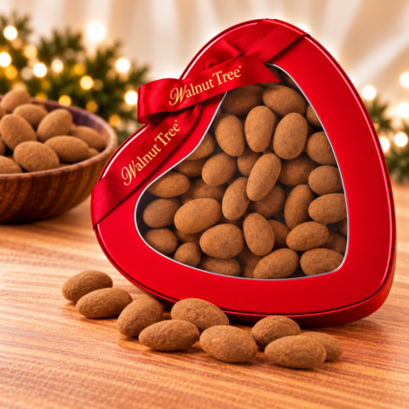Walnut Tree cinnamon-coated almonds presented in a red heart-shaped gift tin with branded ribbon, with loose almonds and a wooden bowl in a festive Christmas setting.