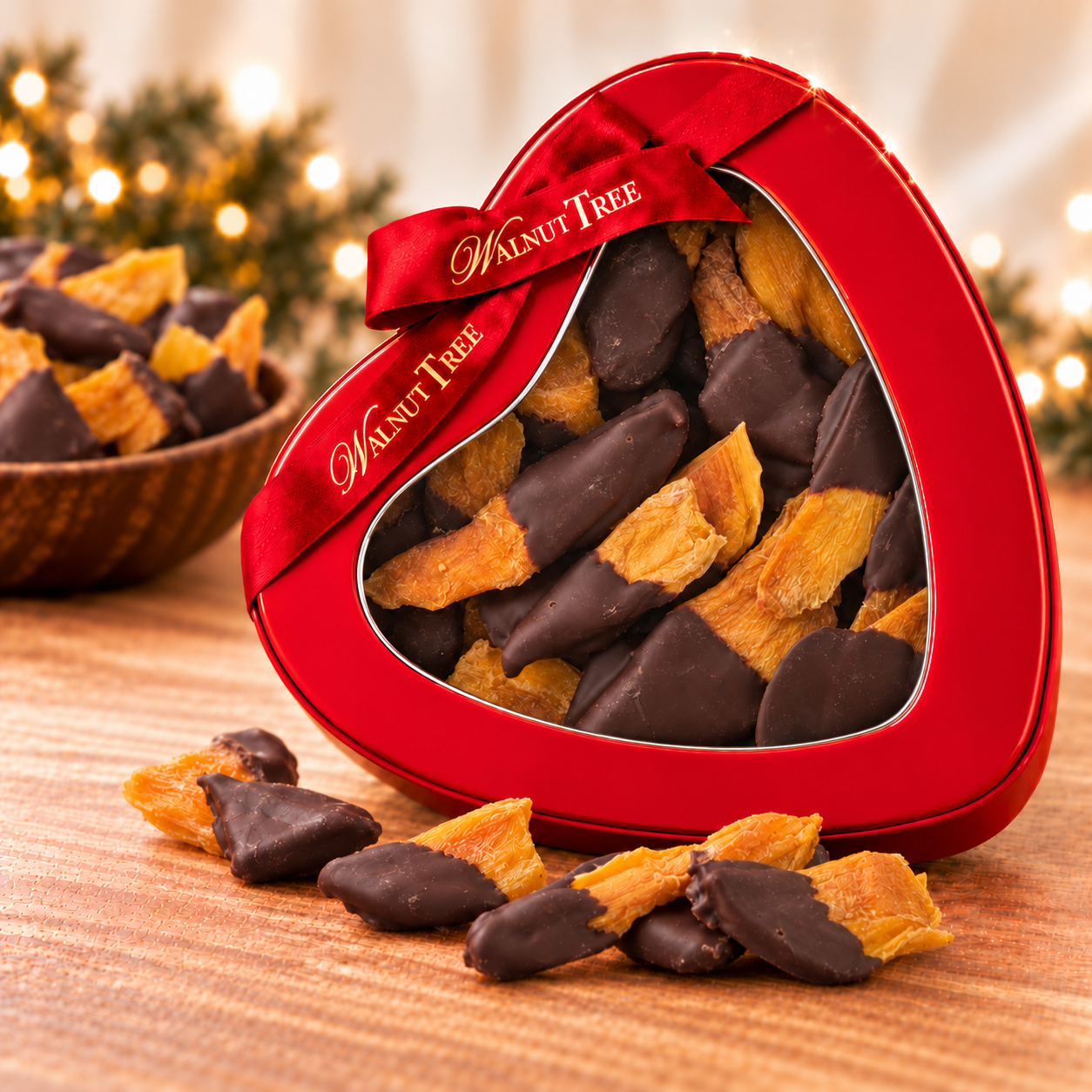 Walnut Tree chocolate-dipped dried mango in a red heart-shaped gift tin with branded ribbon, surrounded by chocolate-covered mango pieces in a festive setting.